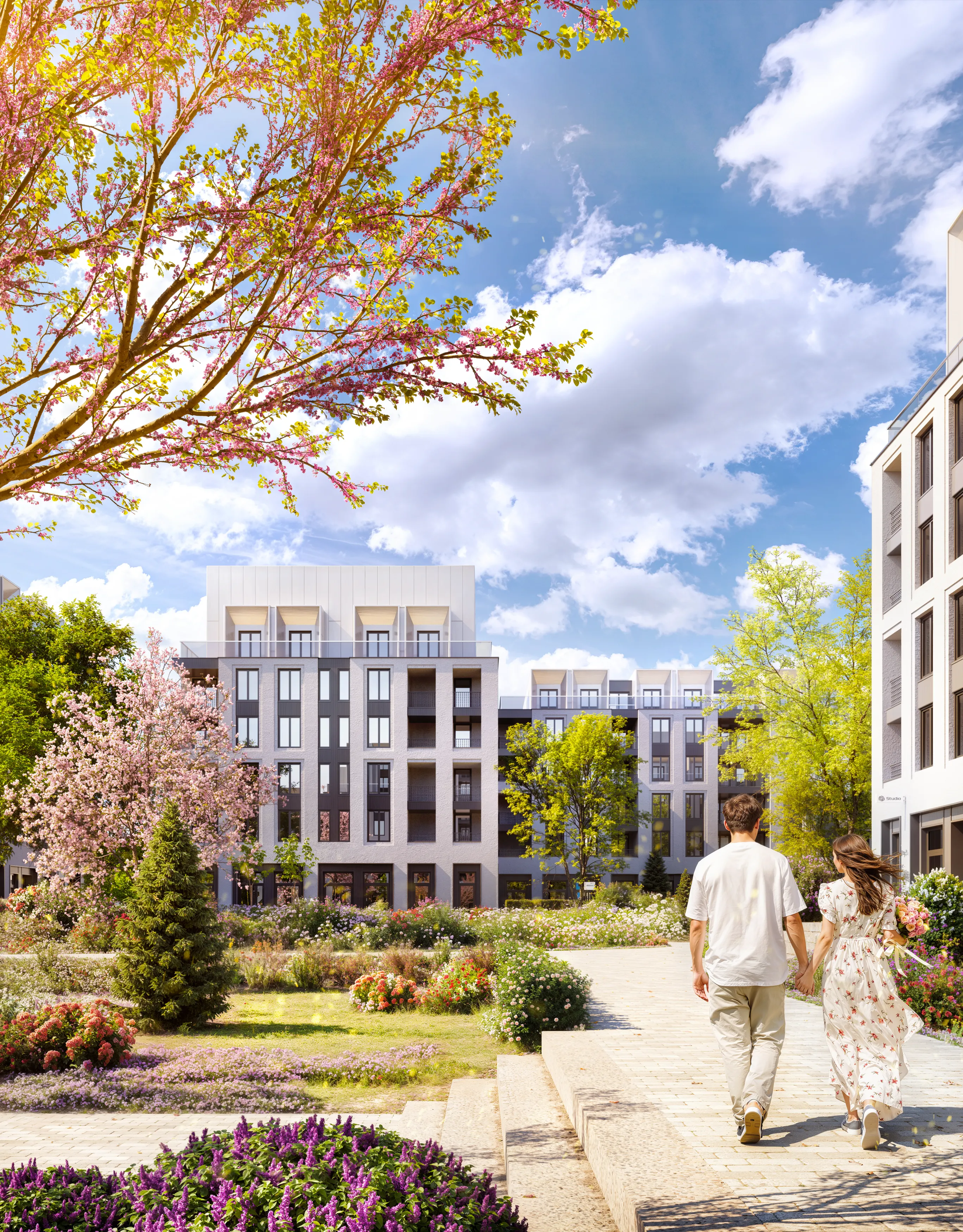 Couple holding hands walking through a landscaped garden with colorful flowers and modern apartment buildings under a partly cloudy sky.