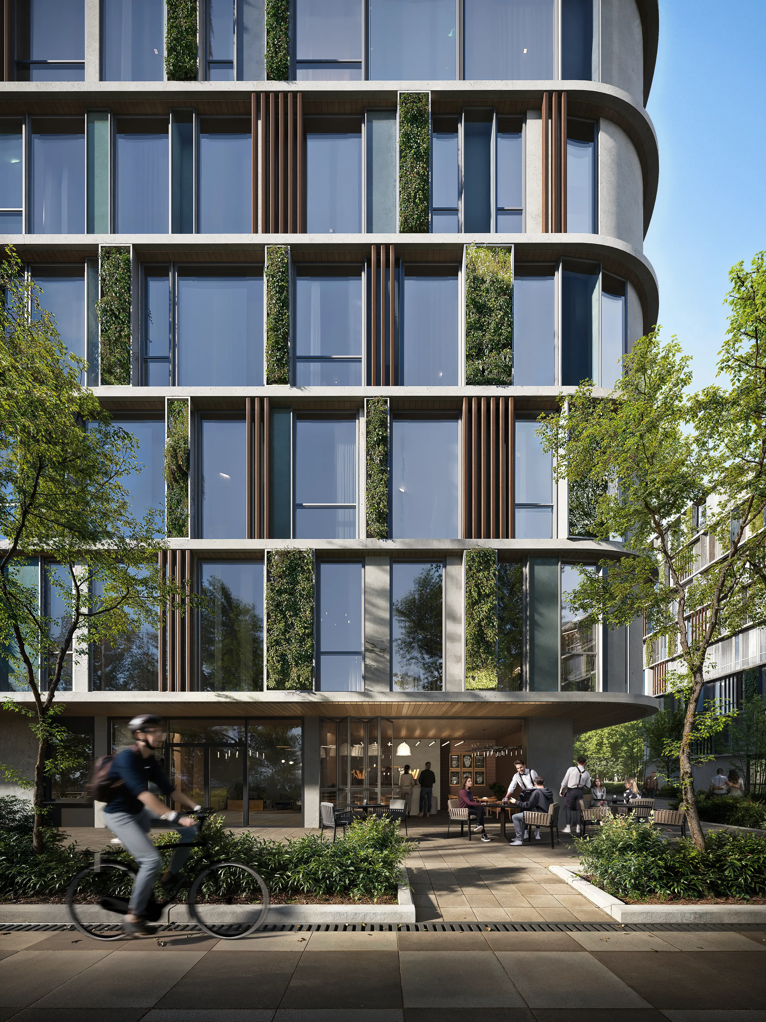 Modern building facade with large glass windows and vertical greenery, people sitting at outdoor tables and a cyclist passing by.