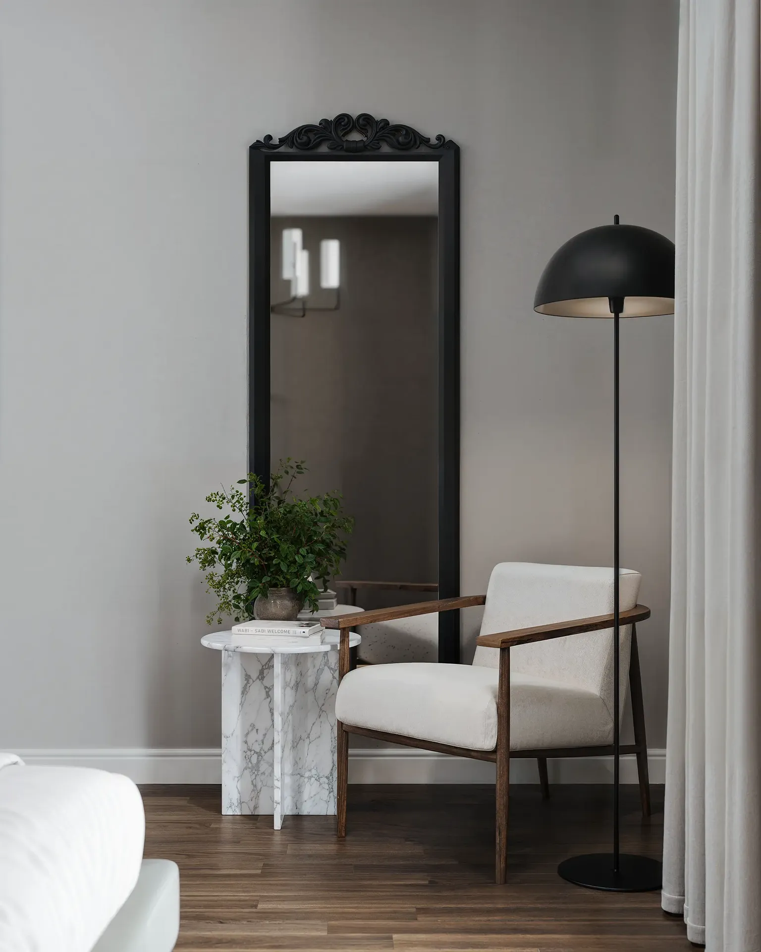Coin salon avec miroir, lampadaire et fauteuil près de la fenêtre.