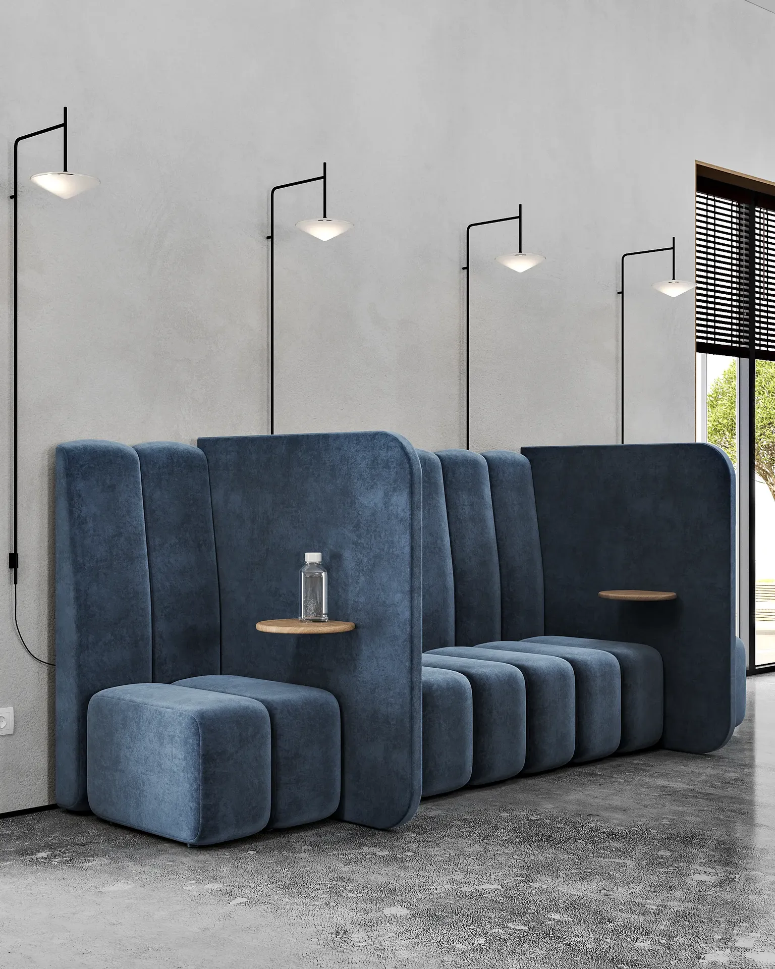 Sala de estar colaborativa con un sofá largo azul, mesas auxiliares y apliques de pared ambientales.