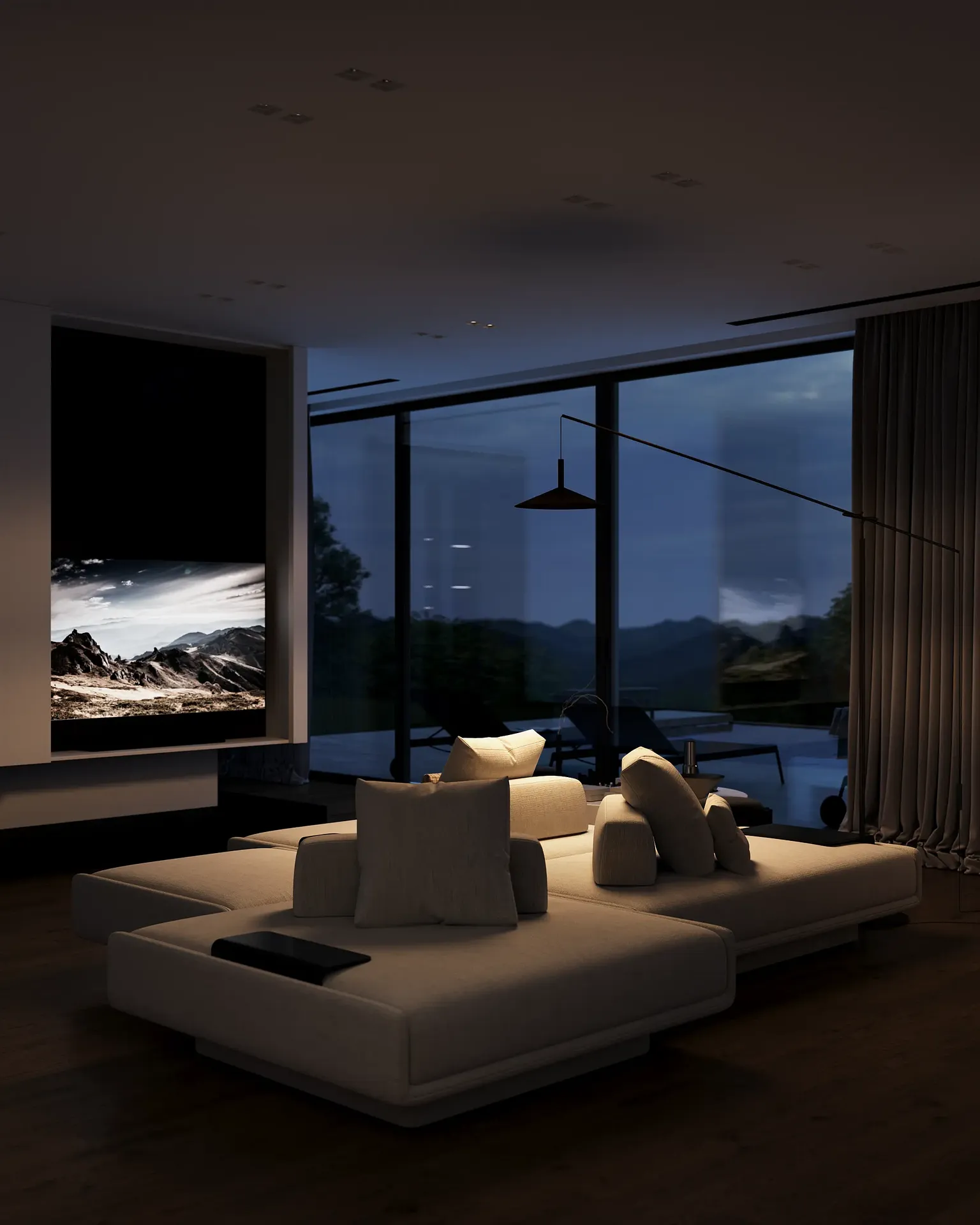 Vue de soirée cosy du salon, montrant le canapé et le coin TV éclairés par un lampadaire chaleureux.